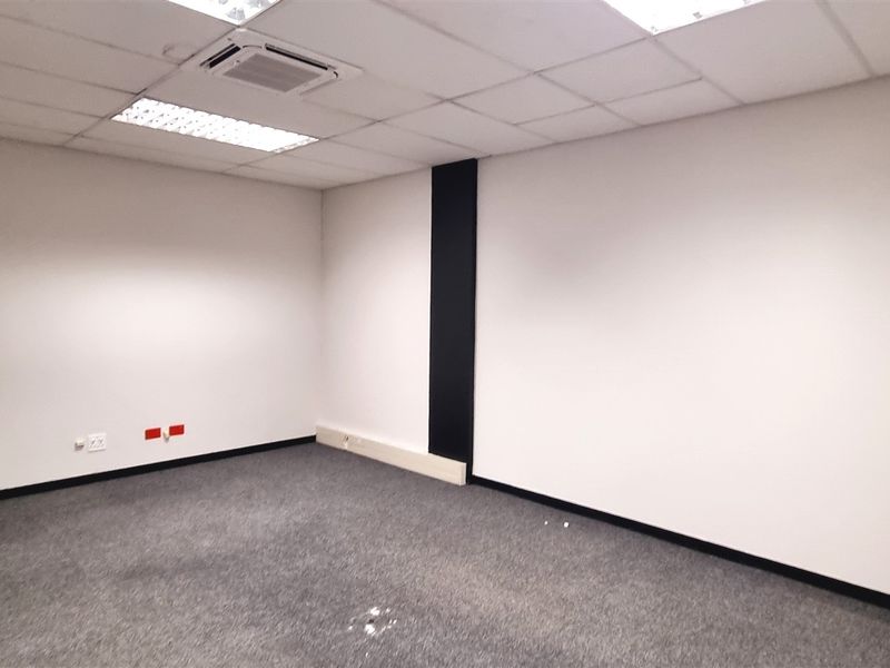 A vacant office space featuring a suspended ceiling with recessed lighting, carpeted flooring, and integrated air conditioning.