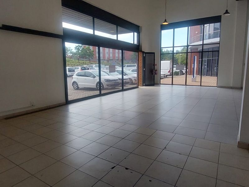 Spacious open-plan retail unit featuring large glass storefront windows, tiled flooring, and high ceilings, offering excellent natural light and visibility.