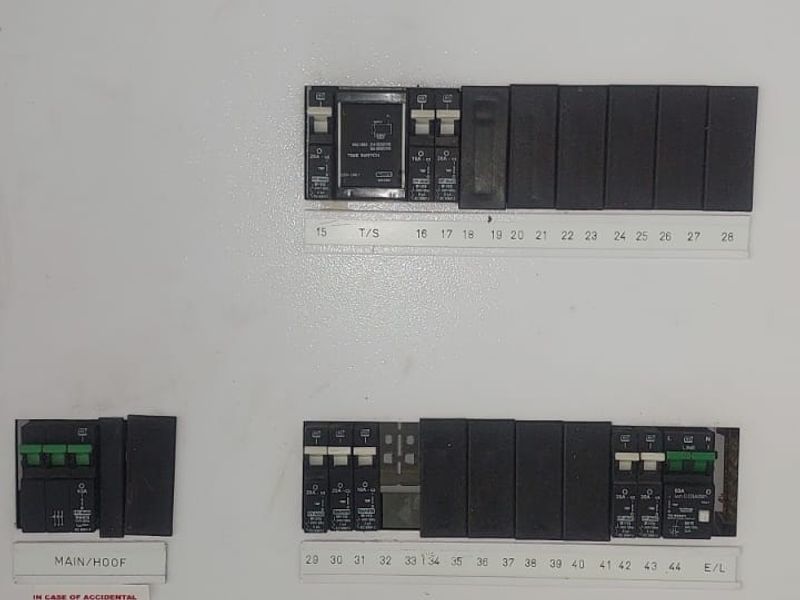 A clean and well-organized electrical distribution board featuring multiple circuit breakers and a main switch for the property's electrical system.