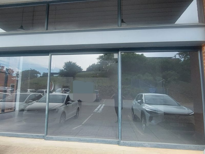 Modern retail storefront featuring large glass display windows, brick facade, and steel structural framing, providing excellent visibility for a commercial business.