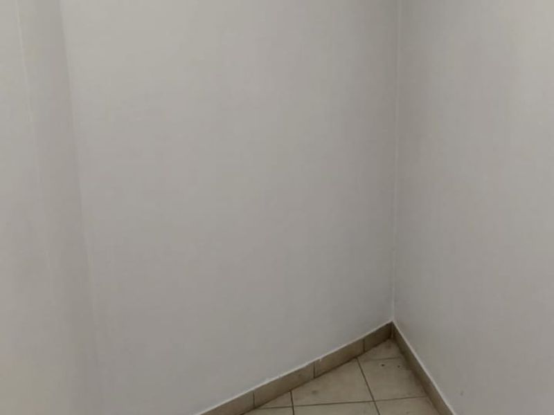 A small, empty utility space featuring neutral floor tiling and plain white walls, suitable for storage or a compact workstation.