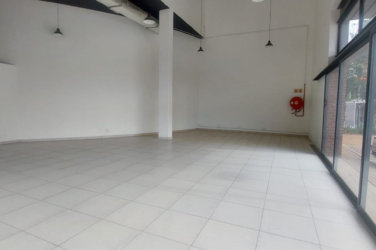 A spacious, open-plan retail unit featuring tiled flooring, high ceilings with exposed ducting, and large glass frontage providing excellent natural light and visibility.