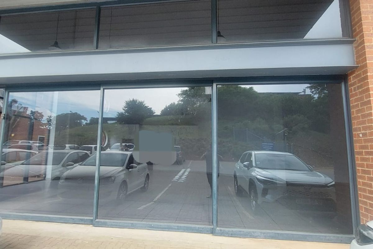 Modern retail storefront featuring large glass display windows, brick facade, and steel structural framing, providing excellent visibility for a commercial business.