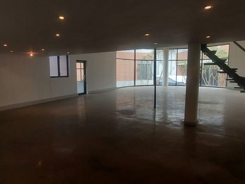 Spacious open-plan retail area featuring polished concrete floors, recessed ceiling lighting, large glass windows, and a modern floating staircase.