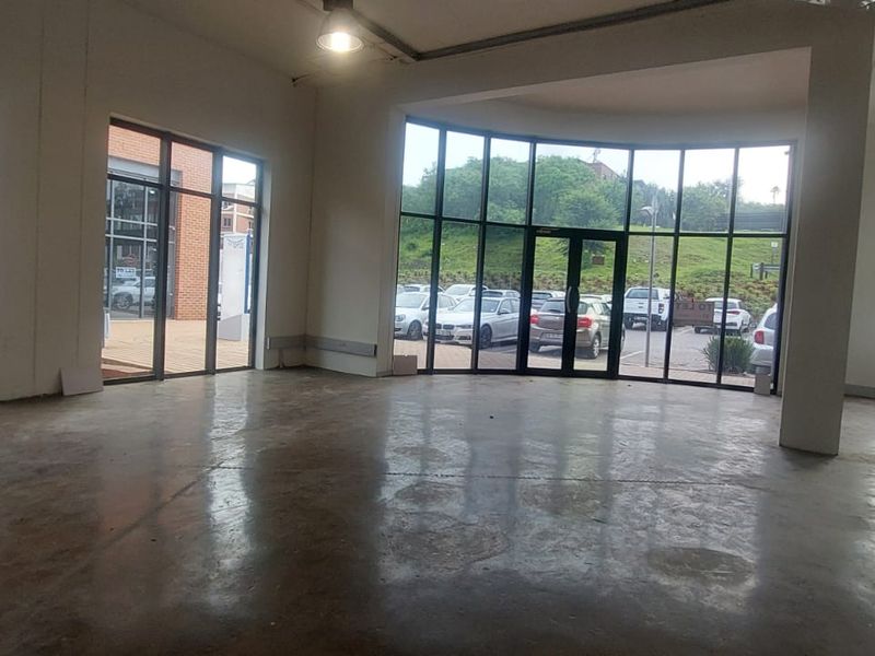Spacious open-plan retail unit featuring polished concrete floors, expansive floor-to-ceiling glass windows, and high ceilings, offering excellent natural light and visibility.