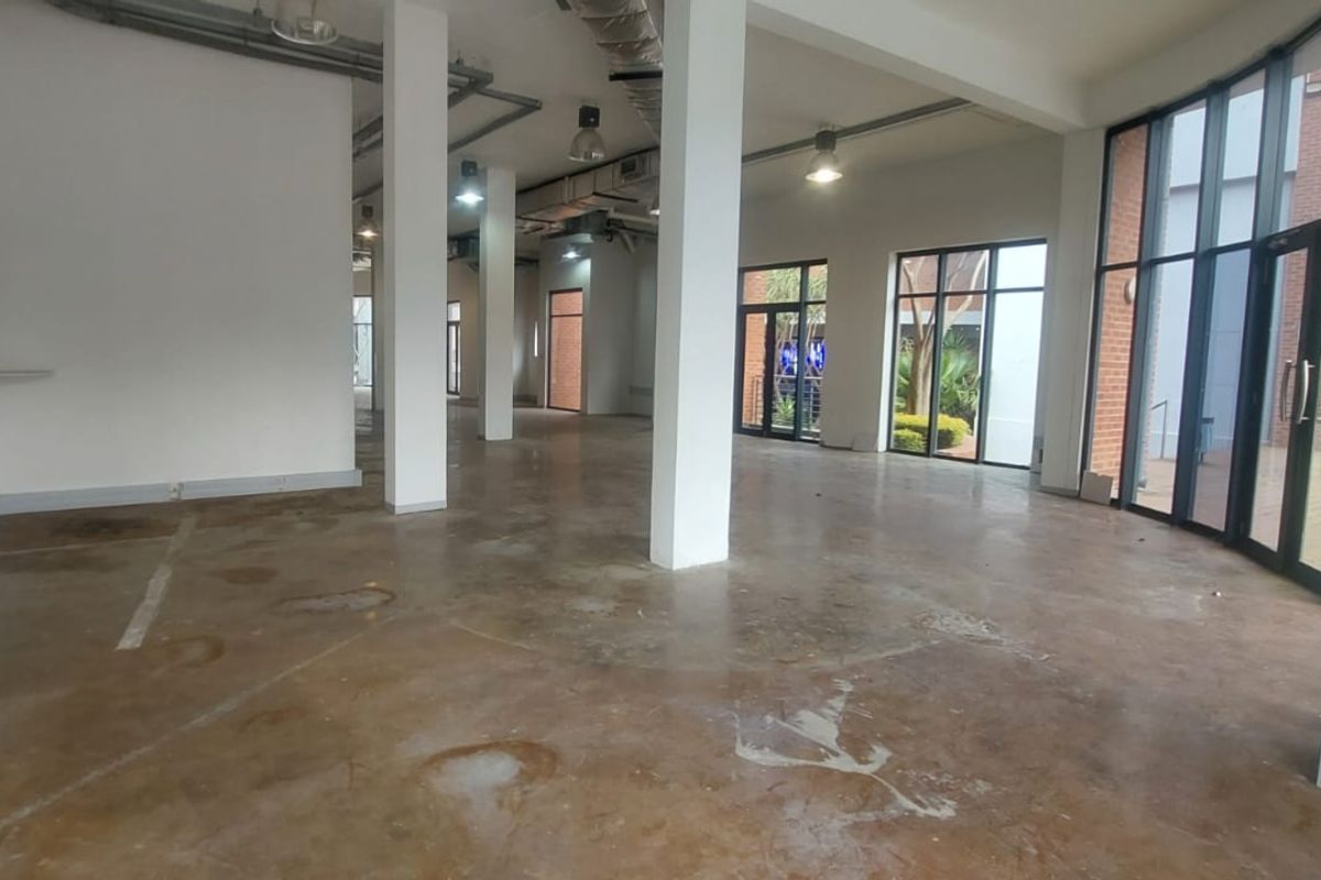 Spacious open-plan retail unit featuring exposed industrial ceilings, concrete flooring, and large glass storefront windows providing ample natural light.