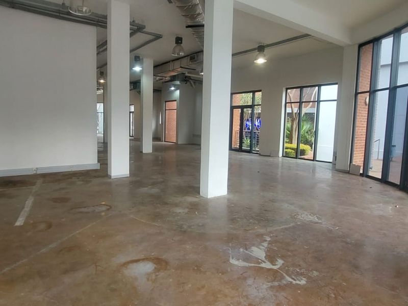Spacious open-plan retail unit featuring exposed industrial ceilings, concrete flooring, and large glass storefront windows providing ample natural light.