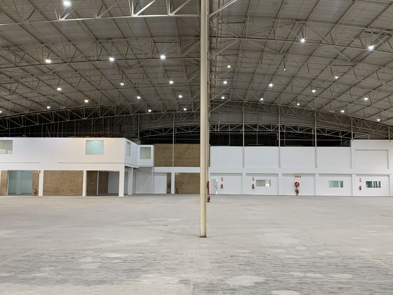 Spacious industrial warehouse featuring high-clearance steel truss roofing, polished concrete flooring, and integrated internal office structures with fire safety equipment.