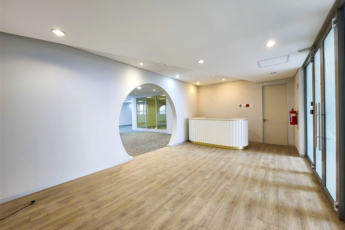 Modern office entrance area featuring a built-in reception desk, wood-look laminate flooring, and a distinctive circular architectural opening leading to the main office space.