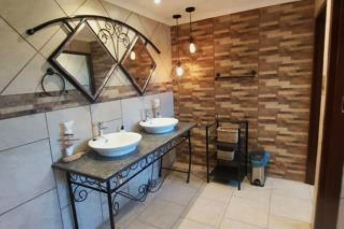 A modern bathroom featuring a double vanity with vessel sinks, decorative tiled wall accents, and stylish pendant lighting.