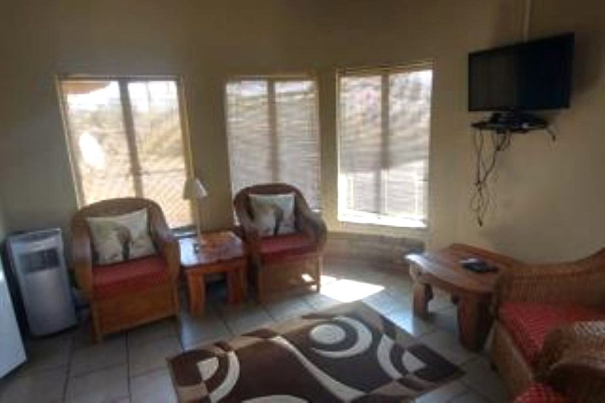 A cozy living room area featuring tiled flooring and large windows that provide natural light, creating a comfortable space for relaxation.