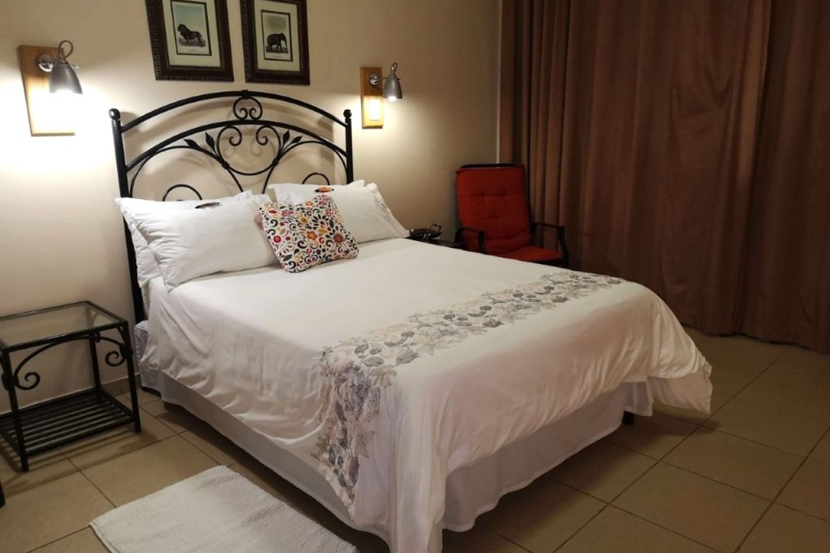 A comfortable bedroom featuring tiled flooring and wall-mounted lighting fixtures, providing a functional and well-lit sleeping space.