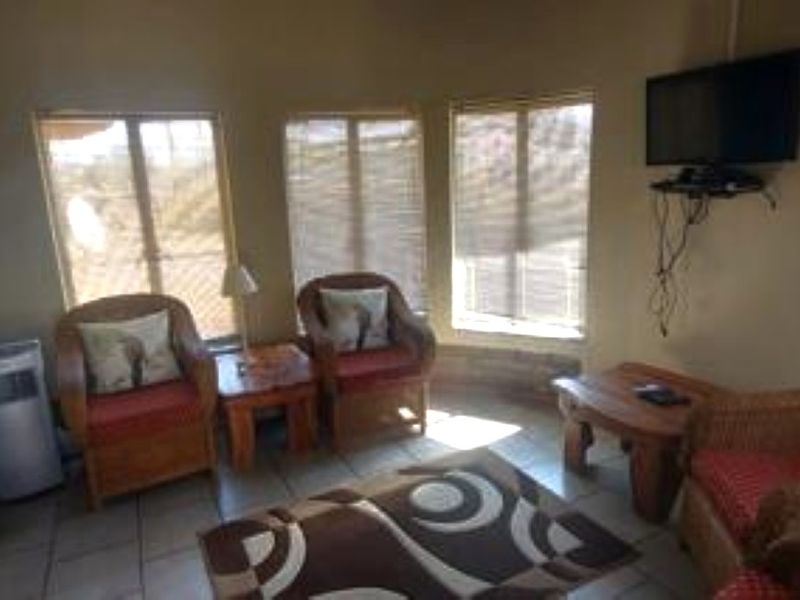 A cozy living room area featuring tiled flooring and large windows that provide natural light, creating a comfortable space for relaxation.