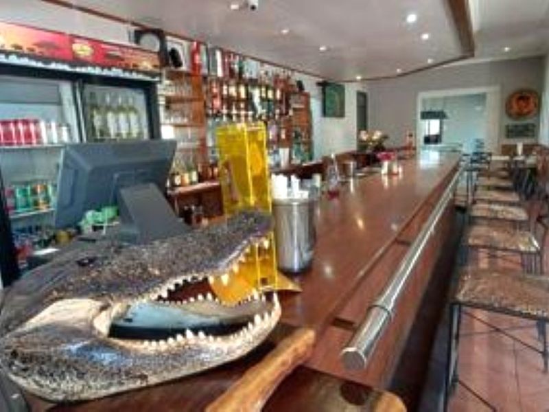 A lodge bar area featuring a long wooden counter, back bar shelving for display, and tiled flooring.