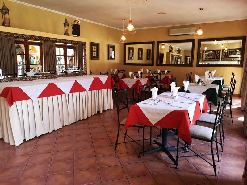 Spacious dining area featuring terracotta floor tiles, wall-mounted air conditioning, and large decorative mirrors, suitable for lodge guest dining or events.