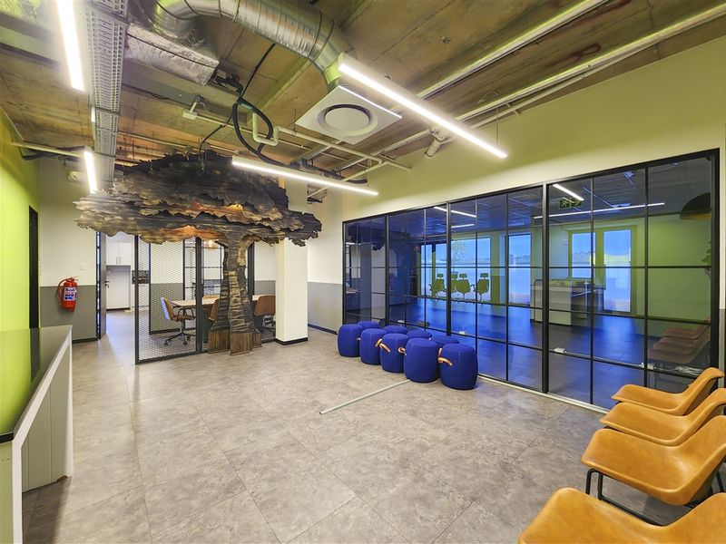 Modern office space featuring an industrial-style exposed ceiling, glass partition walls, and contemporary tiled flooring with integrated lighting.