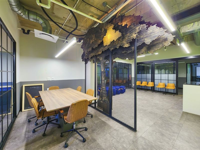 Modern office space featuring an industrial aesthetic with exposed ceilings, decorative metal mesh partitions, and high-quality tiled flooring.