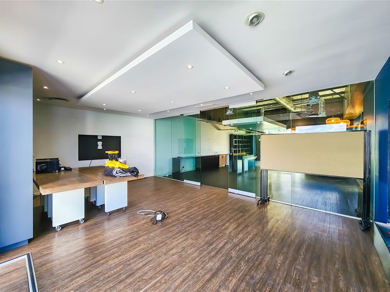 Modern office space featuring glass partition walls, recessed ceiling lighting, and durable laminate flooring, offering a bright and professional work environment.