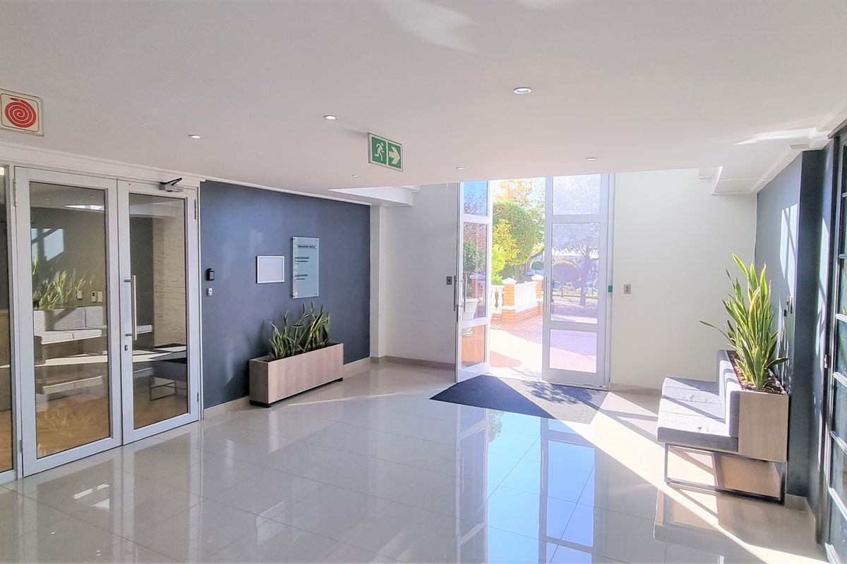Modern office building entrance lobby featuring polished tile flooring, glass partition walls, and bright natural light from the double glass entrance doors.