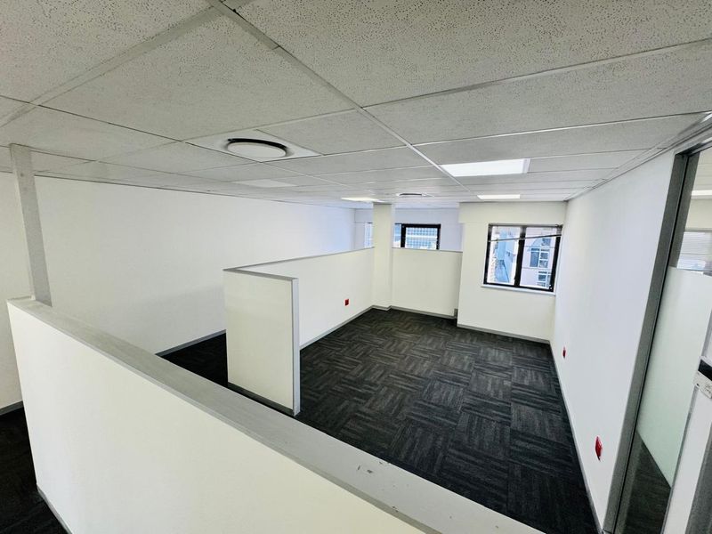 A bright, open-plan office space featuring a suspended ceiling, recessed lighting, and modern carpet tiles, offering a clean and professional work environment.