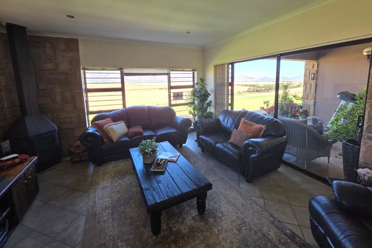 Spacious living room featuring a stone fireplace, tiled flooring, and large sliding glass doors that provide natural light and scenic landscape views.