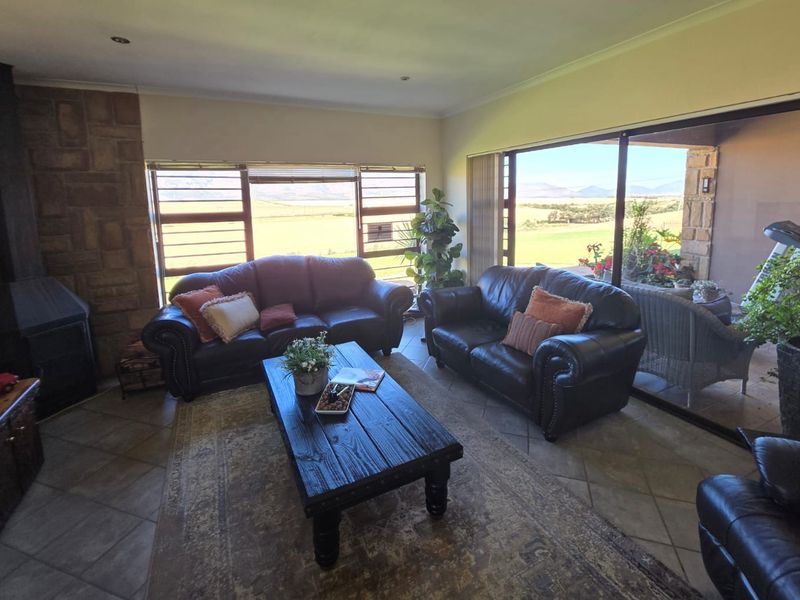 Spacious living room featuring a stone fireplace, tiled flooring, and large sliding glass doors that provide natural light and scenic landscape views.