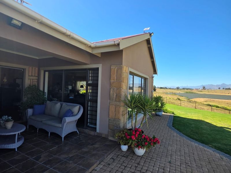 A covered patio area featuring tiled flooring and stone accents, providing seamless access to the garden and scenic landscape views.