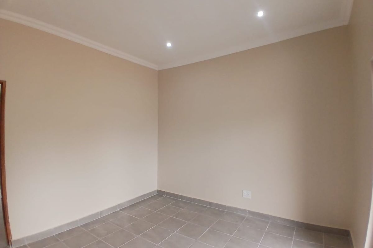 A clean, empty office space featuring neutral walls, tiled flooring, and recessed downlighting, providing a versatile environment for professional use.