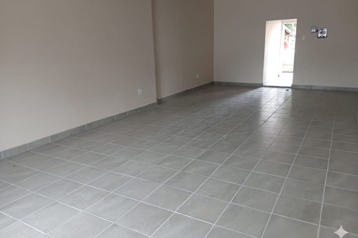 A spacious, empty office area featuring neutral wall tones and durable ceramic floor tiling, providing a clean and versatile workspace.