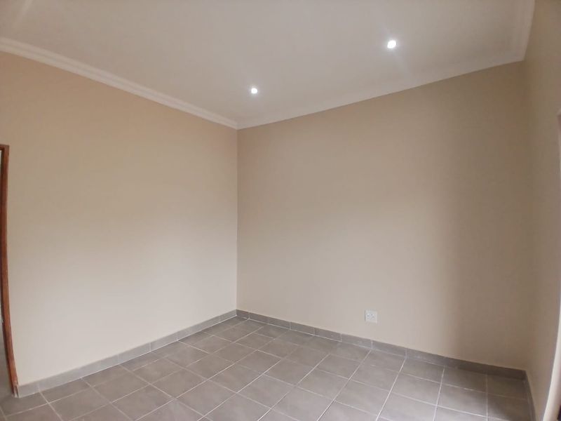 A clean, empty office space featuring neutral walls, tiled flooring, and recessed downlighting, providing a versatile environment for professional use.