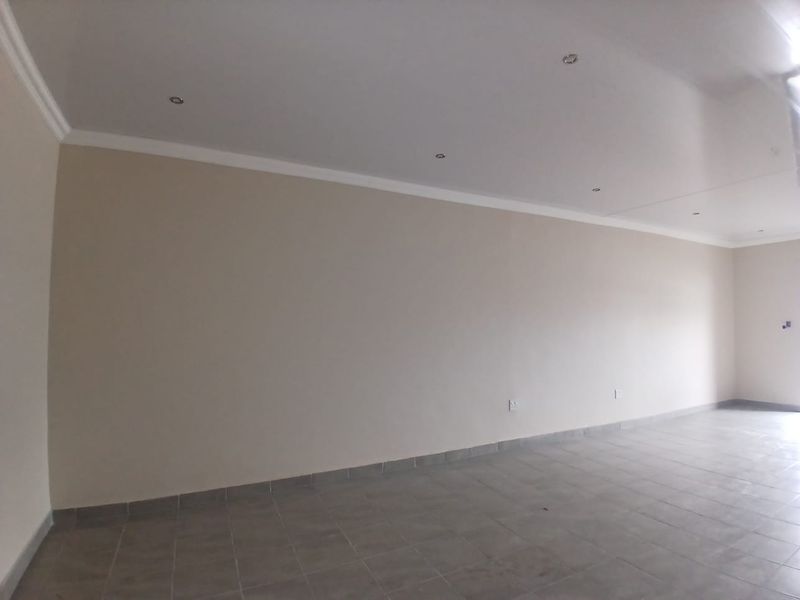 A clean, empty office space featuring neutral walls, tiled flooring, and recessed ceiling lighting, providing a versatile environment for professional use.