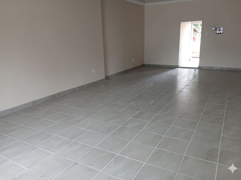 A spacious, empty office area featuring neutral wall tones and durable ceramic floor tiling, providing a clean and versatile workspace.
