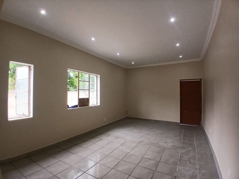 A bright, empty office space featuring neutral walls, tiled flooring, and recessed downlighting, offering a clean and versatile environment for professional use.
