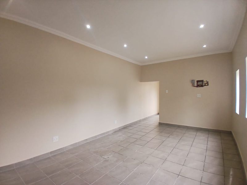 A spacious, empty office area featuring neutral wall tones, ceramic tiled flooring, and recessed ceiling lighting, ready for professional fit-out.