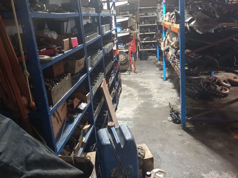 A utility storage area featuring industrial metal shelving units and concrete flooring, currently utilized for parts storage.