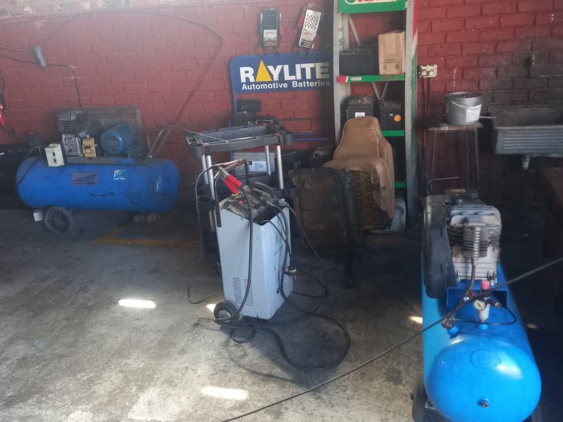 A functional workshop utility space featuring exposed brick walls, concrete flooring, and a built-in utility sink, suitable for automotive or industrial maintenance tasks.