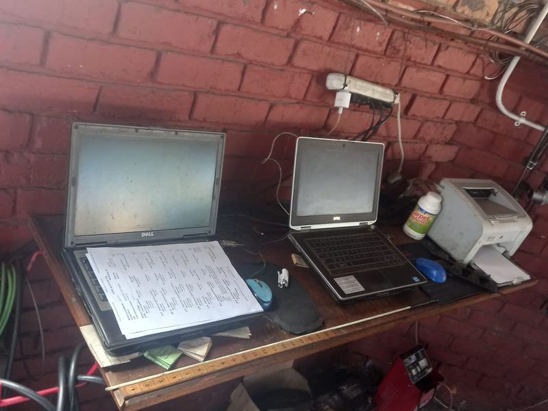 A utility workspace featuring an exposed brick wall with visible electrical wiring and a functional desk setup.