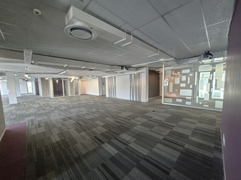 Spacious open-plan office area featuring modern carpet tiles, suspended ceilings with integrated air conditioning, and contemporary glass partitioning for private meeting rooms.