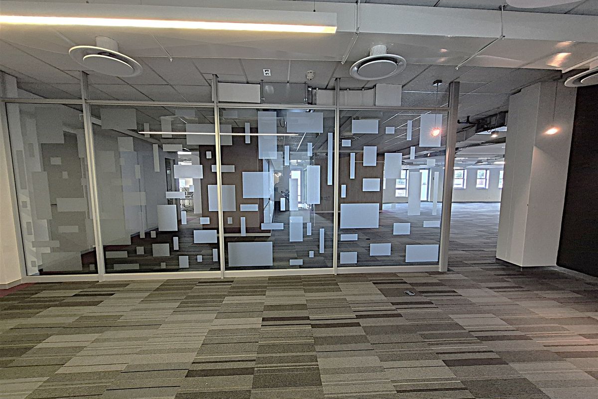 Spacious open-plan office area featuring modern glass partitioning, suspended ceilings with integrated lighting, and durable carpet tile flooring.