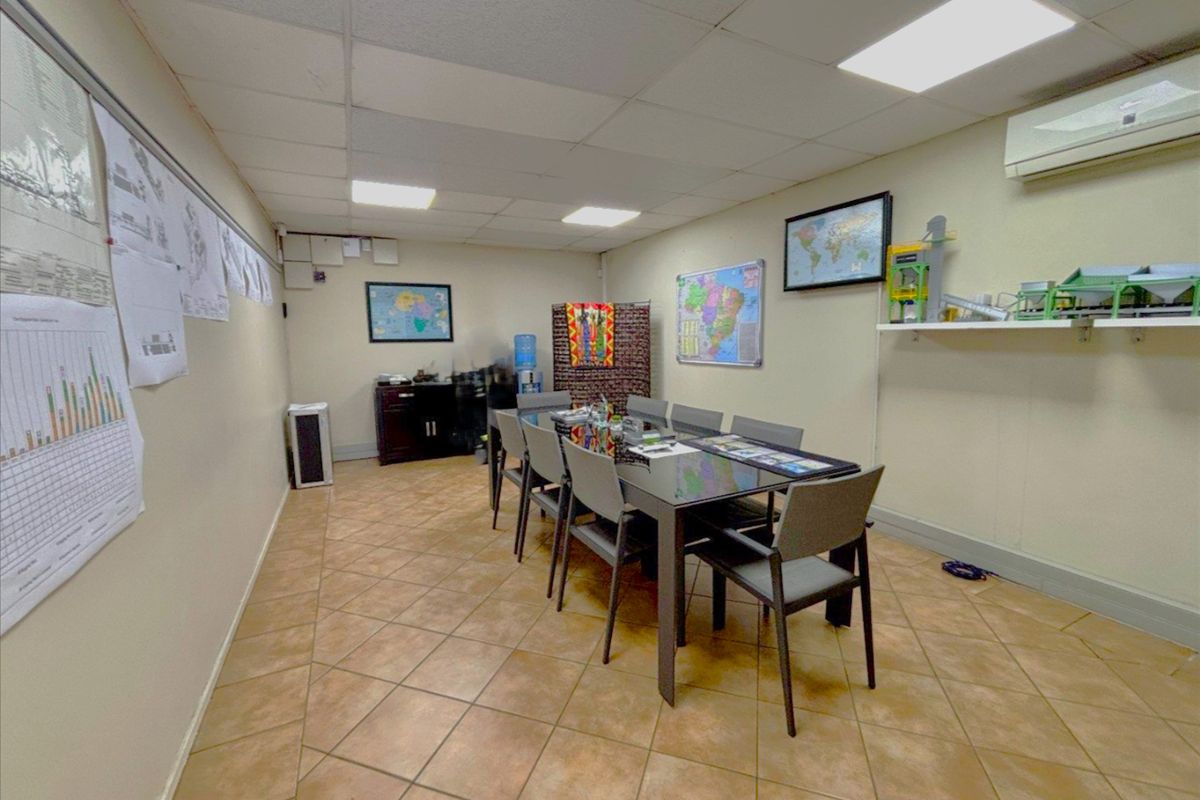 A functional office or meeting room featuring ceramic tile flooring, a suspended ceiling with recessed lighting, and a wall-mounted air conditioning unit.