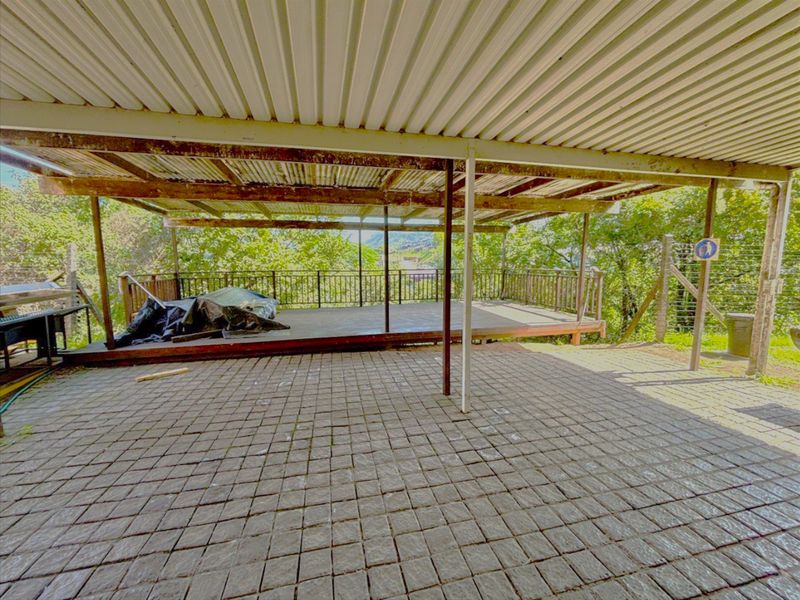 Covered outdoor patio area featuring a paved floor, raised timber deck, and metal roof structure, offering a functional space for industrial or commercial use.
