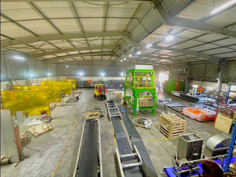 Spacious industrial warehouse facility featuring a high-clearance steel portal frame, concrete flooring, and integrated industrial lighting suitable for manufacturing or storage operations.
