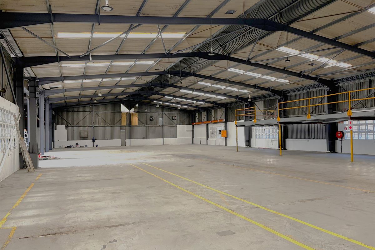 Spacious industrial warehouse featuring a high-clearance steel portal frame, concrete flooring, and an integrated mezzanine level suitable for storage or office conversion.