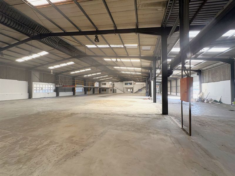 Expansive industrial warehouse space featuring high ceilings, steel portal frame construction, concrete flooring, and a mezzanine level suitable for storage or manufacturing operations.