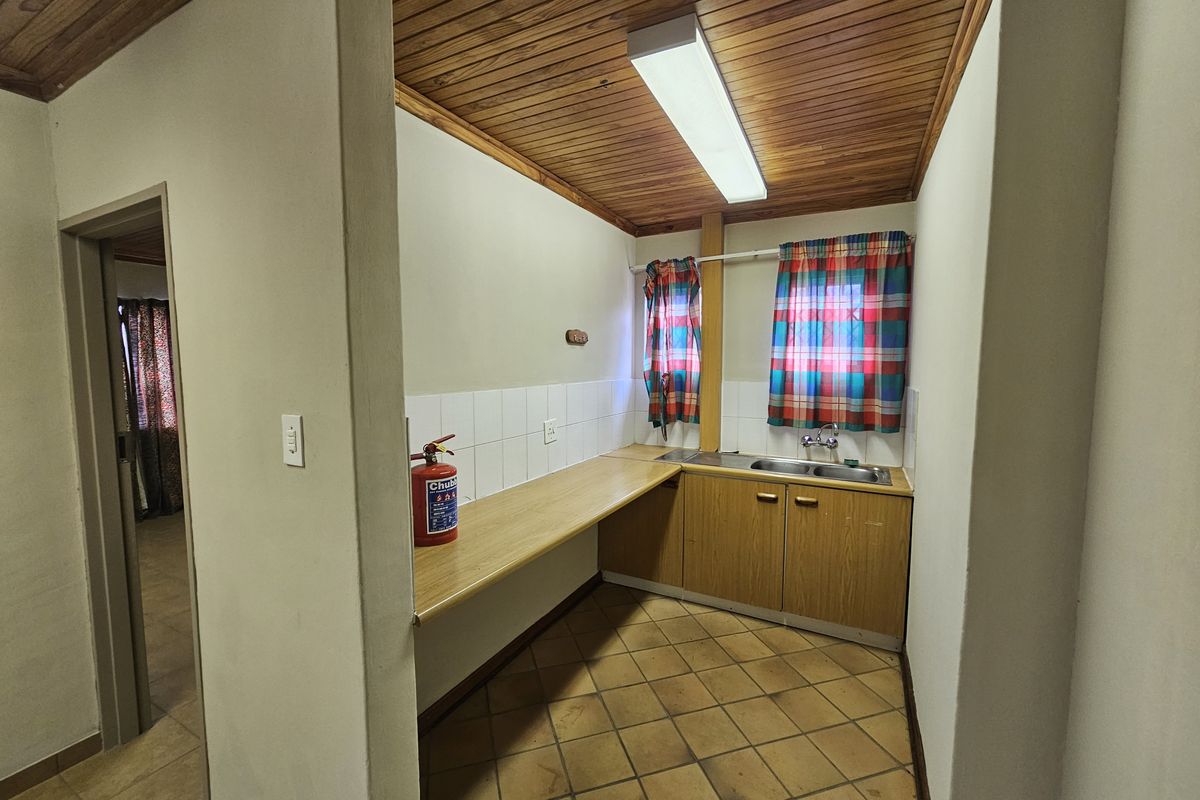 A functional kitchen area featuring built-in wooden cabinetry, a double sink, tiled flooring, and a timber-paneled ceiling.