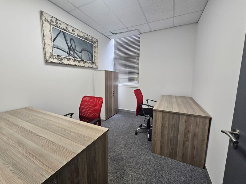 A functional office space featuring a suspended ceiling, carpeted flooring, and window blinds, providing a clean and professional work environment.