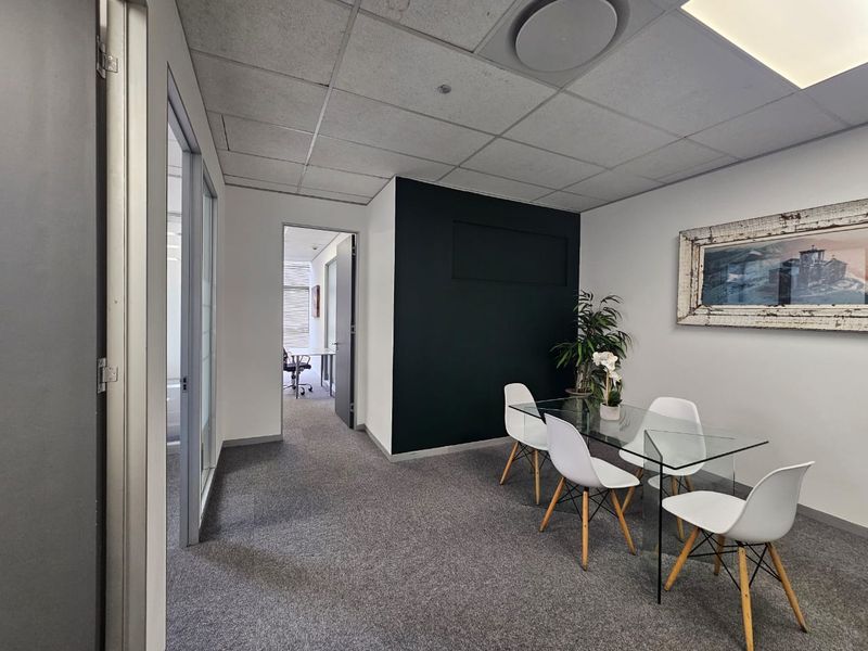 A professional office meeting room featuring a suspended ceiling, recessed lighting, glass partition wall, and carpeted flooring.