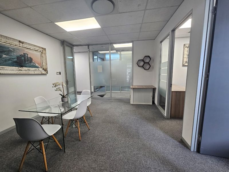 Professional office space featuring glass partition walls, suspended ceilings, and carpeted flooring, providing a clean and functional work environment.