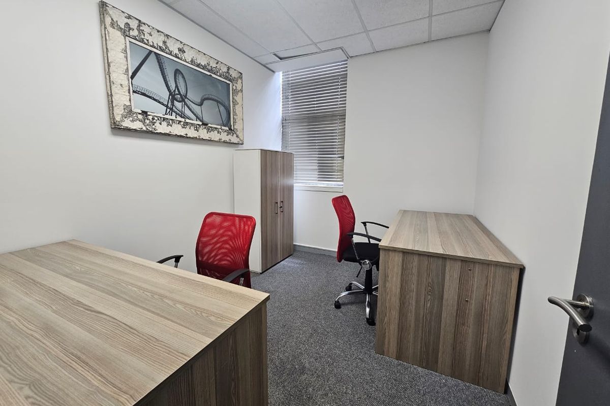 A functional office space featuring a suspended ceiling, carpeted flooring, and window blinds, providing a clean and professional work environment.