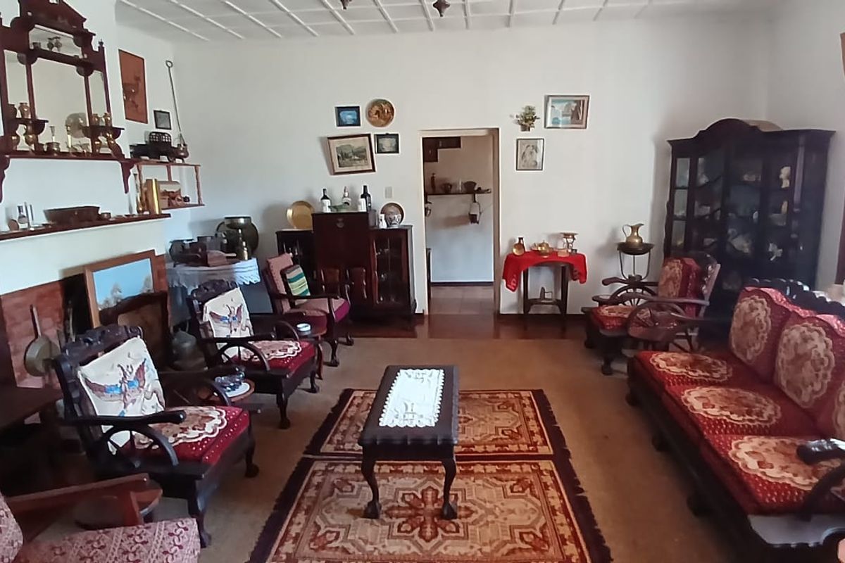 A traditional living room featuring a brick fireplace surround and a tiled ceiling, offering a classic layout with access to an adjacent room.
